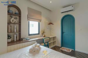 a bedroom with a bed and a blue door and a window at Santorini Homestay Phan Thiet in Tiến Thành