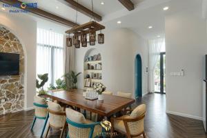 a dining room with a wooden table and chairs at Santorini Homestay Phan Thiet in Tiến Thành