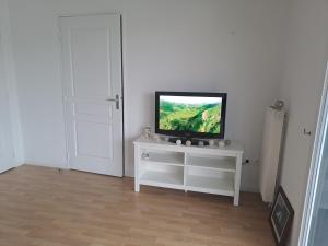 a television sitting on a white stand in a room at Gite des Capucines in Bourbourg