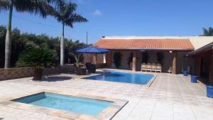 a swimming pool in front of a house at Recanto Barretos in Barretos