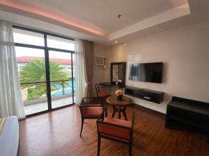 ein Wohnzimmer mit Fernseher und einem Tisch mit Stühlen in der Unterkunft Hotel Oazis in Butuan