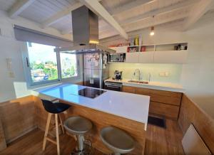 a kitchen with a counter and stools in it at Duplex Premium Ciudad Jardín in El Palomar