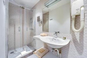 ein weißes Badezimmer mit Waschbecken und Dusche in der Unterkunft Passy Eiffel in Paris