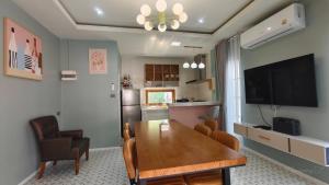 a living room with a dining room table and a television at บ้านออมPool villa บางแสน sin in Ban Bang Saen (1)