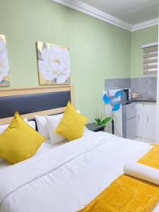 a bedroom with a large white bed with yellow pillows at Stay Arcadia Guest House in Pretoria
