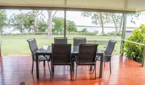 Ein Esstisch und Stühle auf einer Veranda mit Blick auf ein Feld in der Unterkunft Conway in Burrum Heads