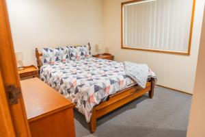 ein Schlafzimmer mit einem Bett, zwei Nachttischen und einem Fenster in der Unterkunft Conway in Burrum Heads
