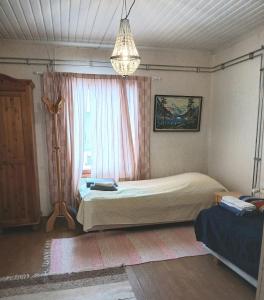 a bedroom with a bed and a window and a chandelier at Villa Sukuviiri in Vimpeli