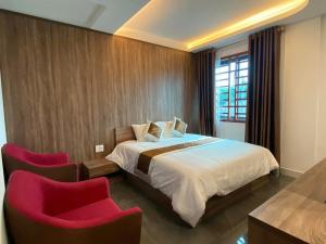 a bedroom with a bed and two red chairs at Hải Phát Hotel in Du Xuyên