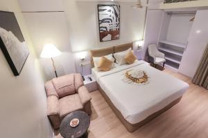 a bedroom with a white bed and a chair at SKYLAR Tirupati in Tirupati
