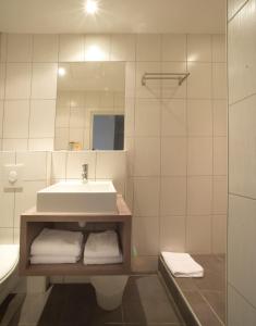ein Badezimmer mit einem Waschbecken, einem Spiegel und Handtüchern in der Unterkunft Hotelo Lyon Charité in Lyon