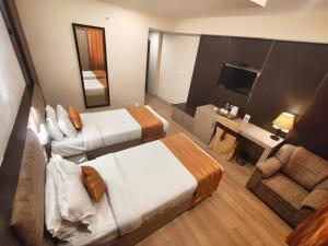 a hotel room with two beds and a couch and a television at SKYLAR Tirupati in Tirupati +11 photos