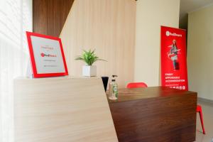 a reception desk with a red sign on top of it at RedDoorz near Gejayan 3 in Yogyakarta