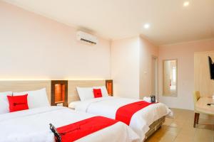 two beds in a hotel room with red pillows at RedDoorz near Gejayan 3 in Yogyakarta