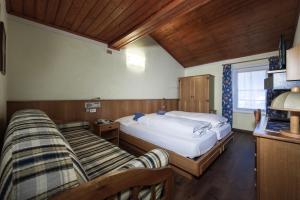 a bedroom with two beds and a couch at Hotel Stella in Moena