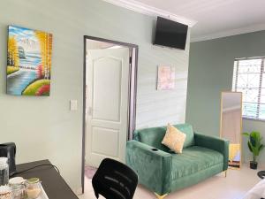a living room with a green chair and a painting at Stay Arcadia Guest House in Pretoria