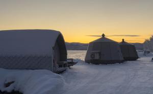 two tents in the snow with the sunset in the background at Aurora Sea Lodges AURORAHUT in Herjenes