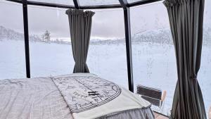 a bedroom with a bed in front of a window at Aurora Sea Lodges AURORAHUT in Herjenes