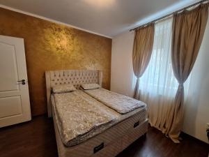 ein Schlafzimmer mit einem Bett und einem Fenster mit Vorhängen in der Unterkunft Duplex Confort Hd in Hunedoara