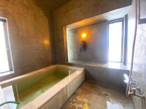 a bath tub in a room with two windows at ROHAUS Entire Home with private Hot Spring in Shiraoi +20 photos
