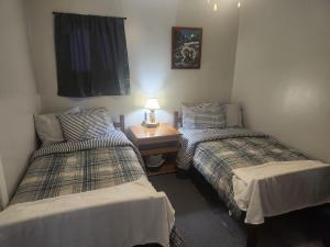 a room with two beds and a table with a lamp at Sword and Dove Rental in Spirit River