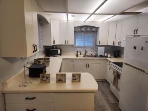 a kitchen with white cabinets and a white refrigerator at Sword and Dove Rental in Spirit River