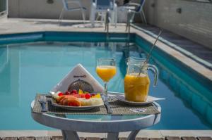 una mesa con una bandeja de fruta y un vaso de zumo de naranja en Mont Blanc Apart Hotel - Duque de Caxias en Duque de Caxias