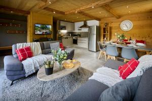 a living room with couches and a table and a kitchen at Le Petit Capricia - OVO Network in La Clusaz