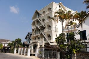 a white building with palm trees in front of it at Là Thông Boutique Đà Lạt in Da Lat
