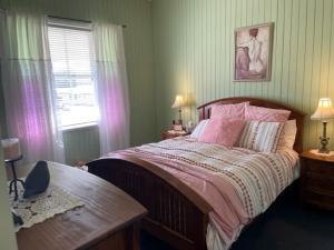 a bedroom with a bed and a table and a window at Marlay Cottage in Stanthorpe
