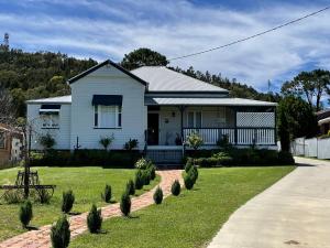 a white house with a lawn and a sidewalk at Marlay Cottage in Stanthorpe