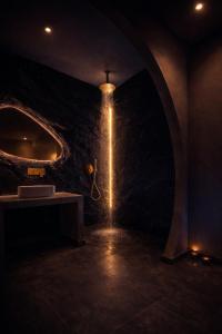 a dark room with a stone wall with a light at Andromeda Suite Private Jacuzzi & Cave Shower in Athens +29 photos