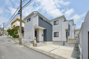 a white and gray house on a street at Aiki No Yado-Kokuba- in Naha