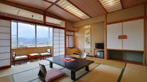 a living room with a table and chairs and windows at かっぱの宿旅館三治郎 in Zao