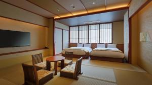 a hotel room with two beds and a television at かっぱの宿旅館三治郎 in Zao