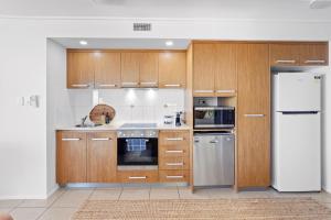 a kitchen with wooden cabinets and a refrigerator at Searene By The Sea in Airlie Beach +6 photos