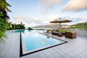 a swimming pool with chairs and an umbrella on a building at Searene By The Sea in Airlie Beach