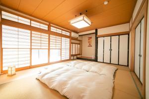 a large white bed in a room with windows at Morioka base モリオカベース in Morioka