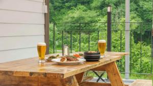 a wooden table with two glasses of beer and food at Gapyeong Nature Pension in Gapyeong