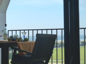 a table with a glass of wine and a chair on a balcony at Apartamento Atlanterra Sol in Zahara de los Atunes