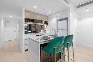 a kitchen with two green chairs at a counter at Matcha Madness Zen Escape - Riverfront in Brisbane