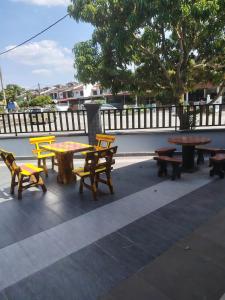 a group of picnic tables and benches on a patio at Jaya's Homestay in Simpang Ampat