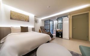 a bedroom with a large white bed and a chair at 호텔벨르 in Pyeongtaek +30 photos