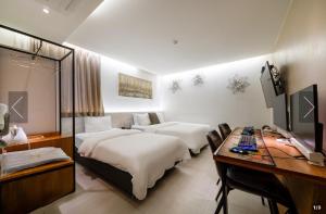 a hotel room with two beds and a desk and a television at 호텔벨르 in Pyeongtaek