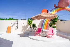 a patio with chairs and an umbrella and a rainbow at Candy House Private Pool Villa & KTV in Ban Nong Chaeng