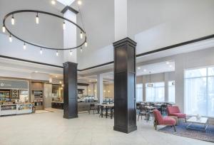 a lobby with tables and chairs and a chandelier at Hilton Garden Inn Raleigh Cary in Cary