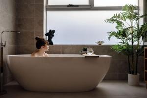 a woman sitting in a bath tub in a bathroom at Elevation in Bicheno