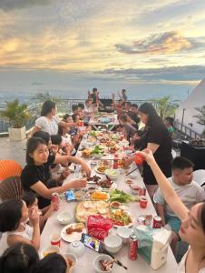 a group of people sitting at a long table eating food at Time Villa in Tam Ðảo