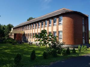a large brick building with a grass field in front of it at Berek Szálló in Balatonfenyves