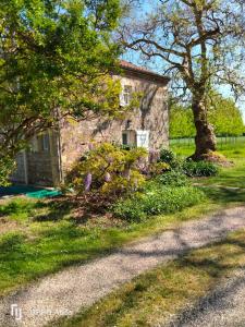 a stone house with trees and flowers in front of it at Bordeneuve in Le Passage